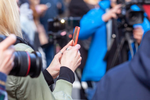 A journalist or influencer using a smartphone under bright light.